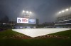 FILE - The tarp covers the infield as rain falls before a scheduled baseball game between the New York Yankees and the Cleveland Guardians on Friday, July 1, 2022, in Cleveland. The game was postponed due to inclement weather. Cleveland was forced to postpone a celebration and flag raising ceremony Tuesday, Sept. 27, to honor its AL Central title before the opener of a three-game series against Tampa Bay due to a rainy weather forecast. This is nothing new to the Guardians, who have been dodging rain drops all season. (AP Photo/Ron Schwane, File)