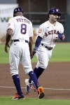 Houston Astros third base coach Gary Pettis (8) low fives Jose Altuve, right, as he rounds third base on his home run during the first inning of a baseball game Tuesday, Sept. 27, 2022, in Houston. (AP Photo/Michael Wyke)