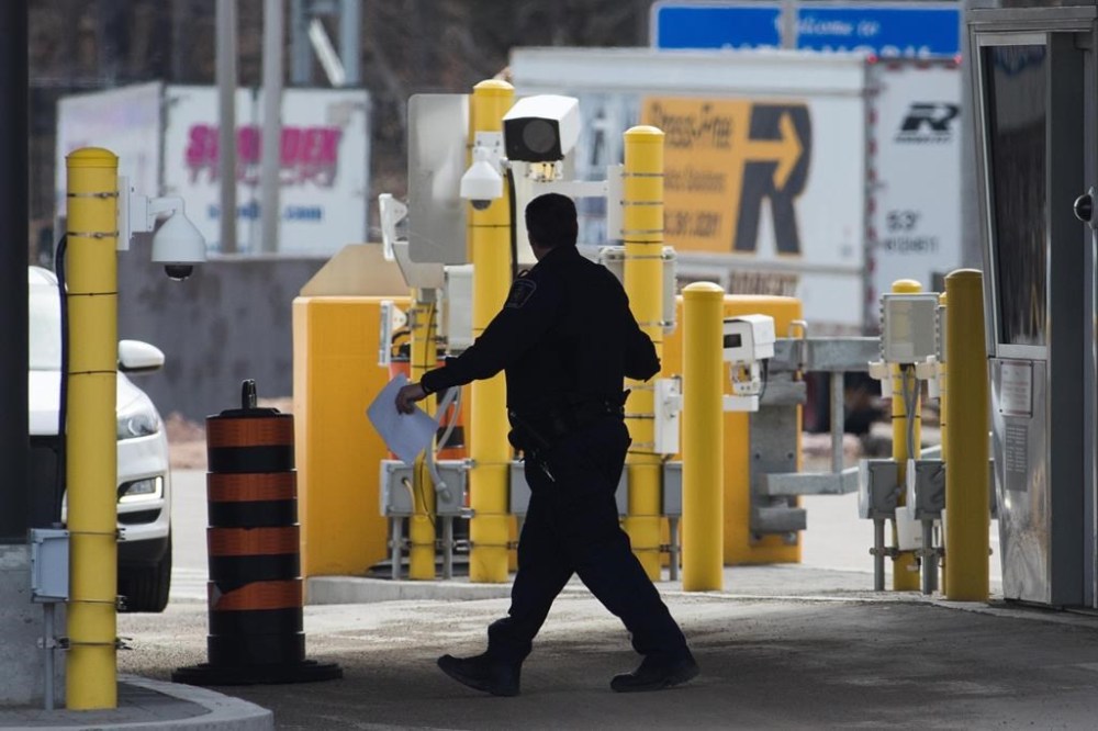 A border officer walks past security cameras at the Thousand Islands border, near Gananqoue, Ont., Monday, March 16, 2020. The federal privacy watchdog says a data breach at a contractor for Canada's border agency involved as many as 1.38 million licence plate images. THE CANADIAN PRESS/Lars Hagberg