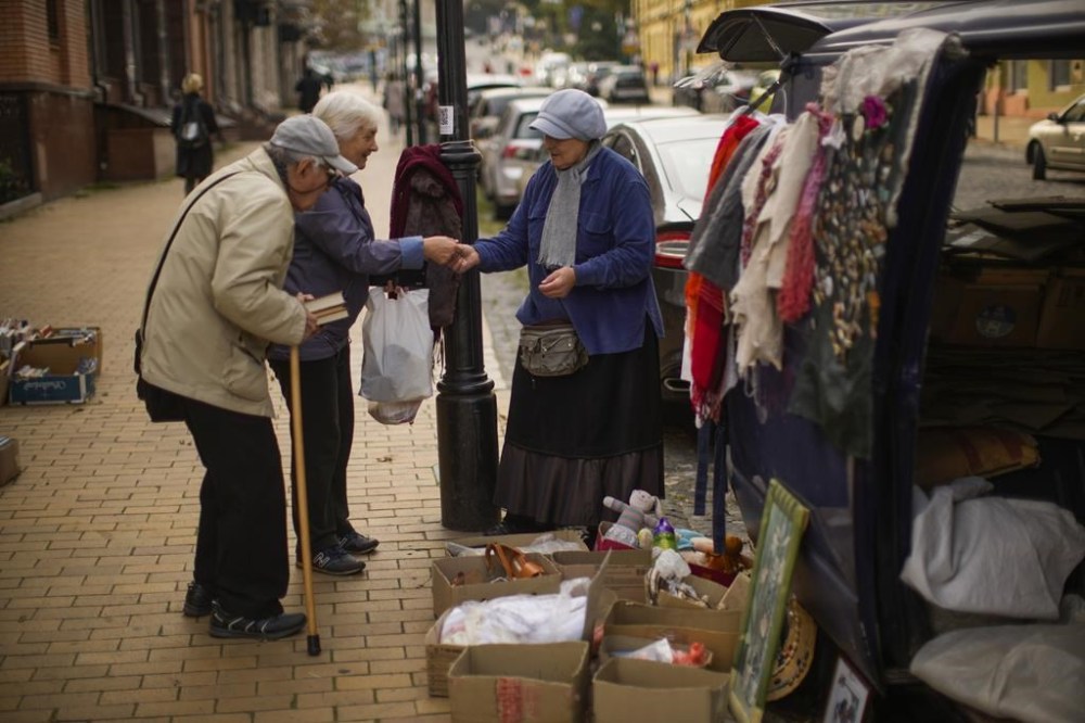 Maria, right, talks to customers as she sells second hand books in Kyiv, Ukraine, Friday, Sept. 30, 2022. (AP Photo/Francisco Seco)