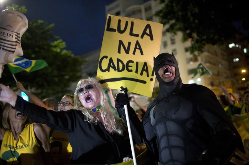 FILE - A demonstrator dressed as Batman holds a sign with a message that reads in Portuguese:
