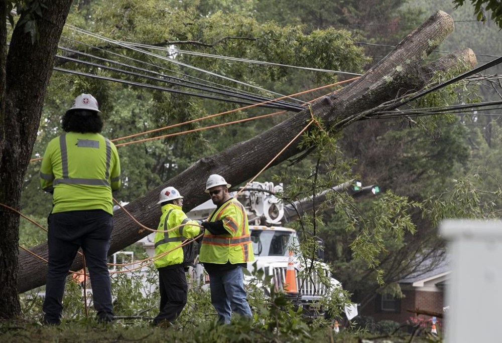 Crews work to clear a tree that fell on power lines on Cole Mill Road following Tropical Storm Ian on Saturday, Oct. 1, 2022, in Durham, N.C. (Kaitlin McKeown/The News & Observer via AP)
