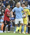 Manchester City's Erling Haaland holds the ball and shakes hand with Manchester United's Lisandro Martinez at the end of the English Premier League soccer match between Manchester City and Manchester United at Etihad stadium in Manchester, England, Sunday, Oct. 2, 2022. Manchester City won 6-3 and he scored an hat trick. (AP Photo/Rui Vieira)