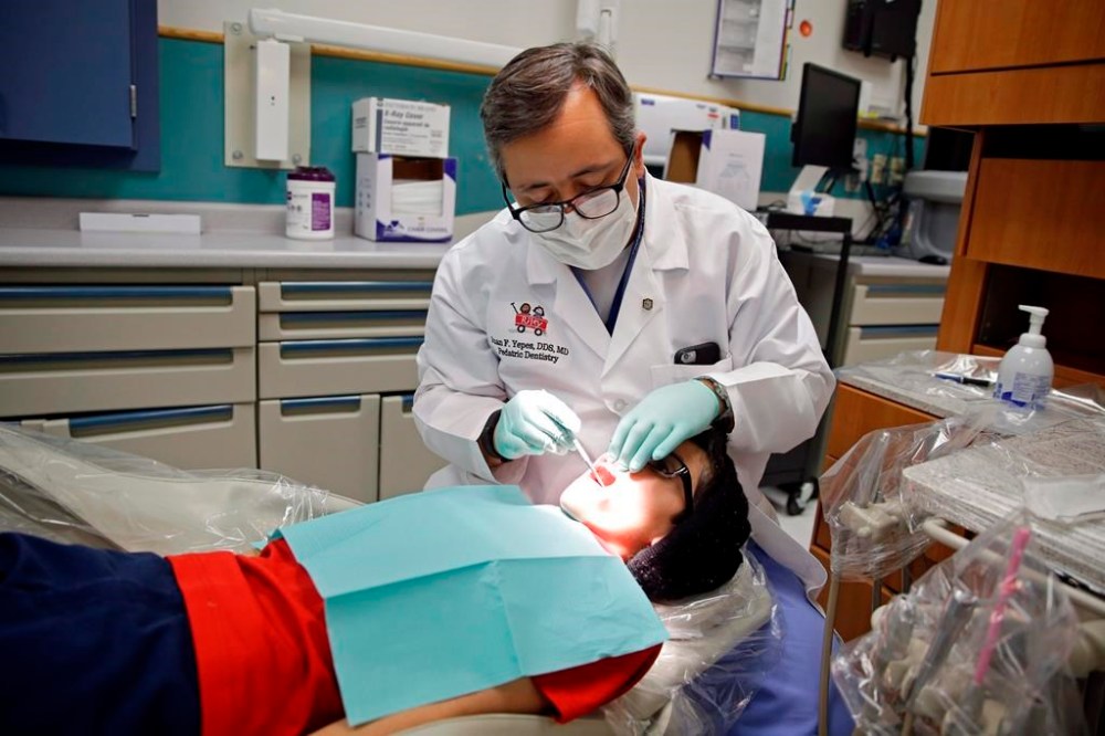 A dentist at the Riley Hospital for Children Department of Pediatric Dentistry, checks the teeth of Justin Perez, 11, during an office visit in Indianapolis, Friday, Jan. 22, 2016. Conservative members of Parliament are arguing the Liberal's dental-care and rental-housing relief legislation will increase inflation rather than provide relief from the rising cost of living.THE CANADIAN PRESS/AP-Michael Conroy
