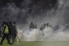 FILE - Police officers and soldiers stand amid tear gas smoke after clashes between fans during a soccer match at Kanjuruhan Stadium in Malang, East Java, Indonesia, Saturday, Oct. 1, 2022. (AP Photo/Yudha Prabow, File)