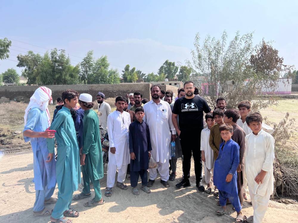 Masroor Khan (wearing a black shirt) with people affected by flooding in Pakistan. (Supplied)