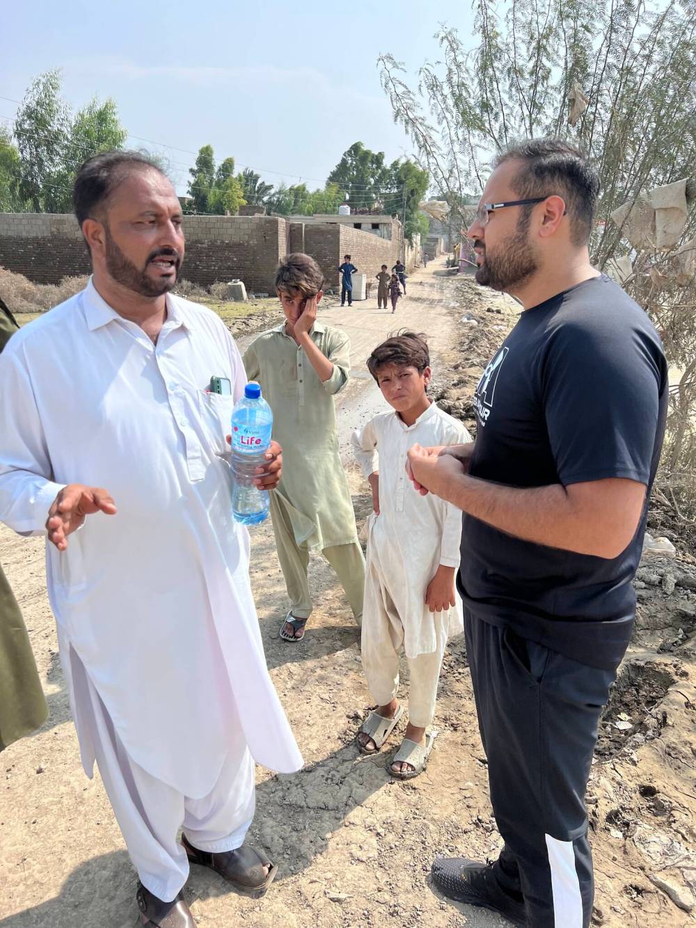 Masroor Khan, right, speaks to a flood survivor in Pakistan. (Supplied)