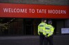 Police officers patrol the entrance of Tate Modern gallery, in London, Saturday, Oct. 15, 2022. Climate protesters threw soup over Vincent van Gogh's 