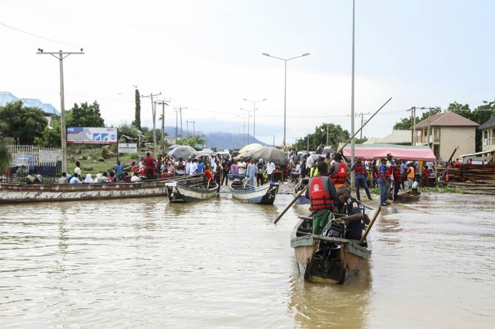 FILE- People stranded due to floods following several days of downpours, in Kogi Nigeria, Thursday, Oct. 6, 2022. Officials in Nigeria say the death toll from this year's flooding has now risen to 603. Authorities have called the floods the country's worst in more than a decade, blaming the disaster on unusually heavy rainfall and the release of excess water from the Lagdo dam in neighboring Cameroon. (AP Photo/Fatai Campbell, File)