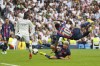 Barcelona's Sergi Roberto and Ansu Fati, right, fall to the ground in front of Real Madrid's Ferland Mendy during a Spanish La Liga soccer match between Real Madrid and Barcelona at the Santiago Bernabeu stadium in Madrid, Sunday, Oct. 16, 2022. (AP Photo/Manu Fernandez)