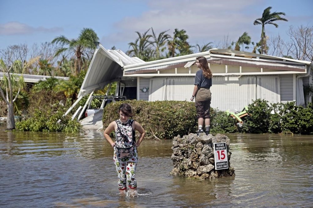 Sammie Clark, 11, left, and Nevaeh Curran, 11, explore a flooded mobile home community in Iona, an unincorporated community in Lee County near Fort Myers, Fla., Sept. 29, 2022. Florida has seen an increase in cases of flesh-eating bacteria this year driven largely by a surge in the county hit hardest by Hurricane Ian. The state Department of Health reports that as of Friday there have been 65 cases of vibrio vulnificus infections and 11 deaths in Florida this year. That compares to 34 cases and 10 deaths reported during all of 2021. (Amy Beth Bennett/South Florida Sun-Sentinel via AP)