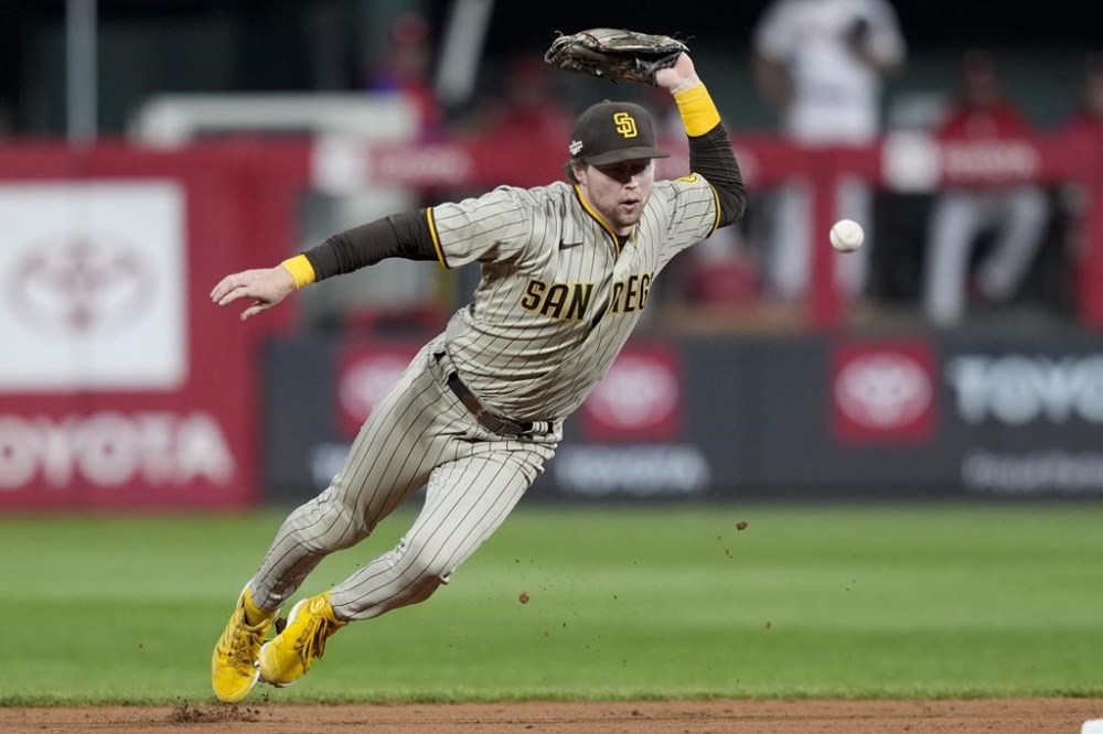 San Diego Padres second baseman Jake Cronenworth can't get a glove on a single by Philadelphia Phillies' Nick Castellanos during the fifth inning in Game 4 of the baseball NL Championship Series between the San Diego Padres and the Philadelphia Phillies on Saturday, Oct. 22, 2022, in Philadelphia. (AP Photo/Matt Slocum)