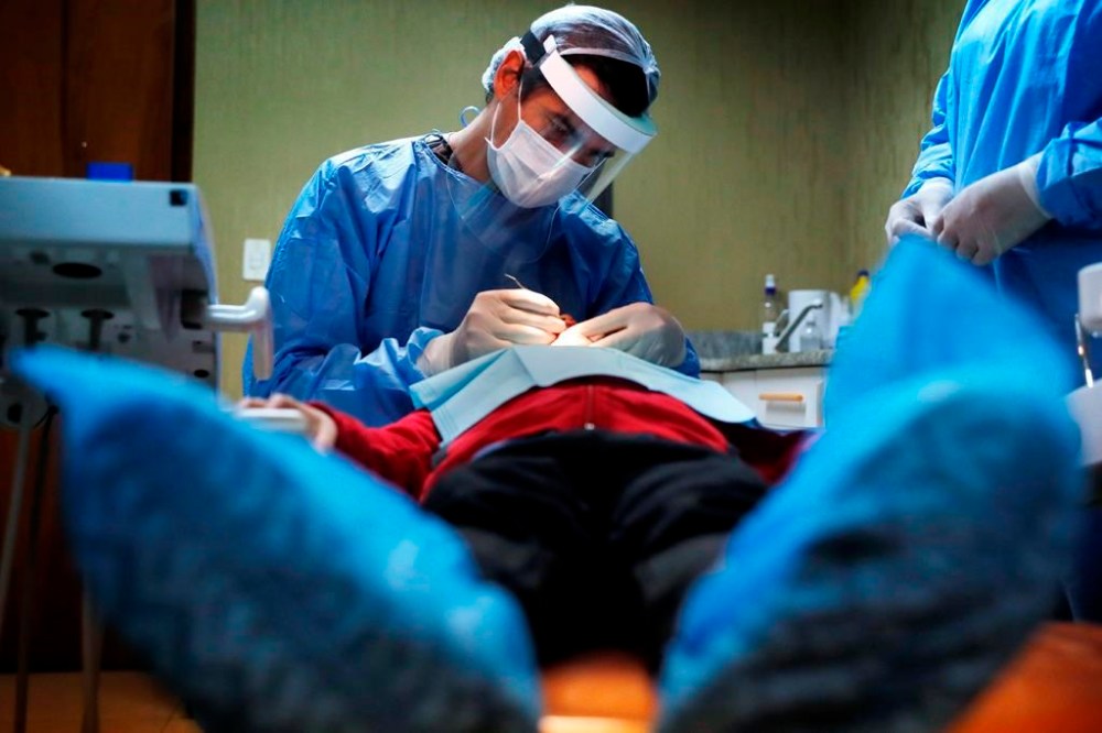 A dentist attends to a child at a family clinic in Asuncion, Paraguay, Tuesday, June 2, 2020. Health department officials say the federal government plans to hire a third-party company to process claims for its new dental-care insurance program. THE CANADIAN PRESS/AP, Jorge Saenz