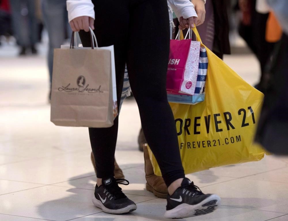A shopper carries their purchases in shopping bags as they walk in Ottawa's Rideau Centre mall on Boxing Day, Wednesday, Dec. 26, 2018. Stores are making it harder and more costly to bring back items just as consumers hooked on online shopping during the pandemic are making more returns than ever.THE CANADIAN PRESS/Justin Tang