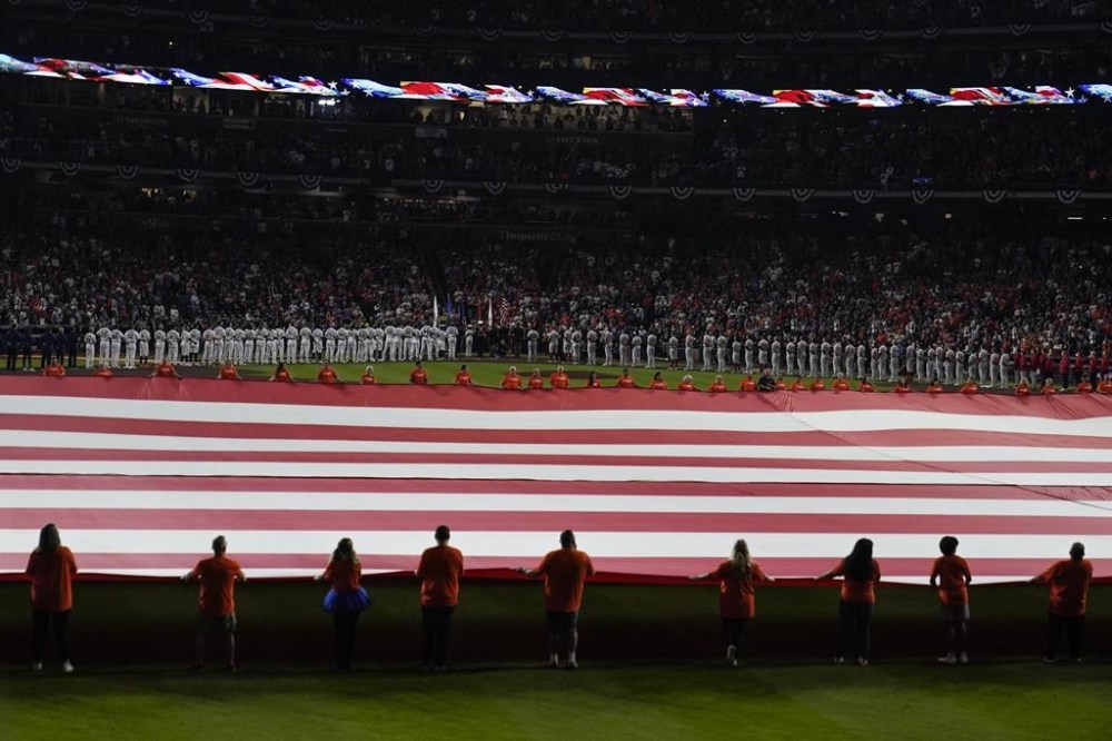 The American flag is unfurled during the national anthem beforeGame 1 of baseball's World Series between the Houston Astros and the Philadelphia Phillies on Friday, Oct. 28, 2022, in Houston. (AP Photo/Sue Ogrocki)