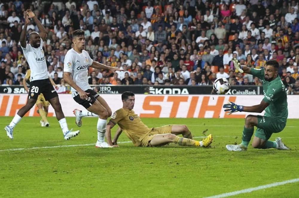Barcelona's Robert Lewandowski, centre, scores the opening goal in extra time during a Spanish La Liga soccer match between Valencia and Barcelona at the Mestalla stadium in Valencia, Spain, Saturday, Oct. 29, 2022. (AP Photo/Alberto Saiz)