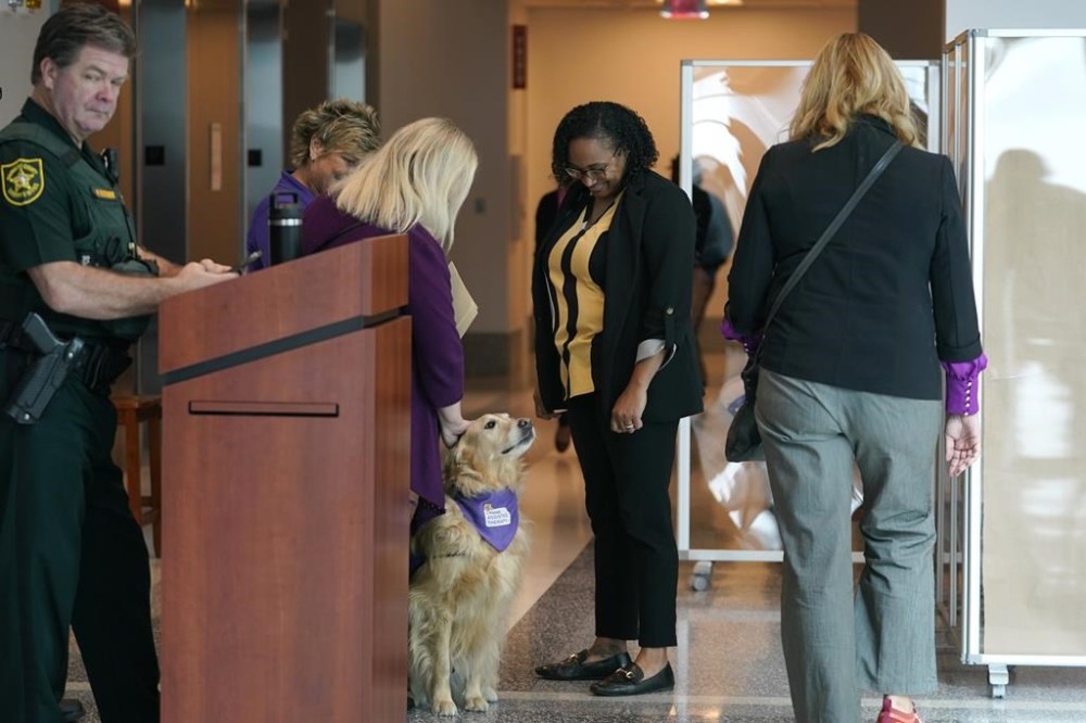 Bree Wikander, third from left, pets a therapy dog outside the courtroom at the Broward County Courthouse for the sentencing hearing of Florida school shooter Nikolas Cruz, Tuesday, Nov. 1, 2022, in Fort Lauderdale, Fla. Cruz was sentenced to life in prison for murdering 17 people at Parkland's Marjory Stoneman Douglas High School more than four years ago. Wikander's son Benjamin was injured in the shooting. (AP Photo/Lynne Sladky, Pool)