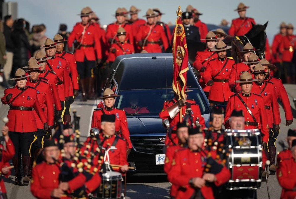RCMP officers in red serge march alongside a hearse carrying RCMP Const. Shaelyn Yang's casket to her regimental funeral, in Richmond, B.C., on Wednesday, November 2, 2022. The 31-year-old officer was stabbed to death two weeks ago while she helped a City of Burnaby employee issue an eviction notice to a man living in a tent at a local park. THE CANADIAN PRESS/Darryl Dyck