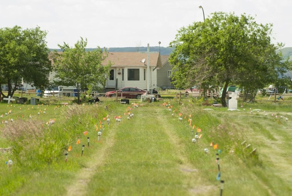 Flags mark where ground-penetrating radar recorded hits of what are believed to be 751 unmarked graves in this cemetery near the grounds of the former Marieval Indian Residential School on the Cowessess First Nation, Sask., Saturday, June 26, 2021. An independent official appointed to help communities investigate unmarked graves at former residential school sites says she is exploring the idea of whether a special tribunal should prosecute or investigate related crimes. THE CANADIAN PRESS/Mark Taylor