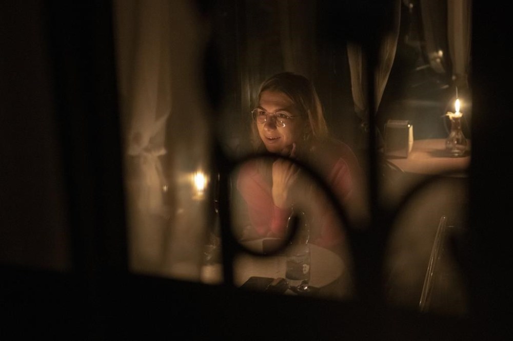 A woman sits in a caffe during a blackout in Kyiv, Ukraine, Friday, Nov. 4, 2022. (AP Photo/Andrew Kravchenko)