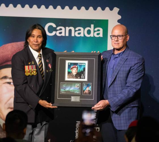 Tommy Prince Jr. (left) is presented with a stamp of his father, Sgt. Tommy Prince, Monday at the Canadian Museum for Human Rights. (Jessica Lee / Winnipeg Free Press)