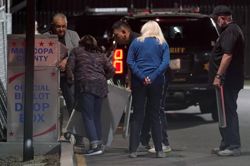 Maricopa County Recorders officials and law enforcement retrieve ballots in a drop-box after the polls closed outside the Maricopa County Recorders Office, Tuesday, Nov. 8, 2022, in Phoenix. (AP Photo/Matt York)