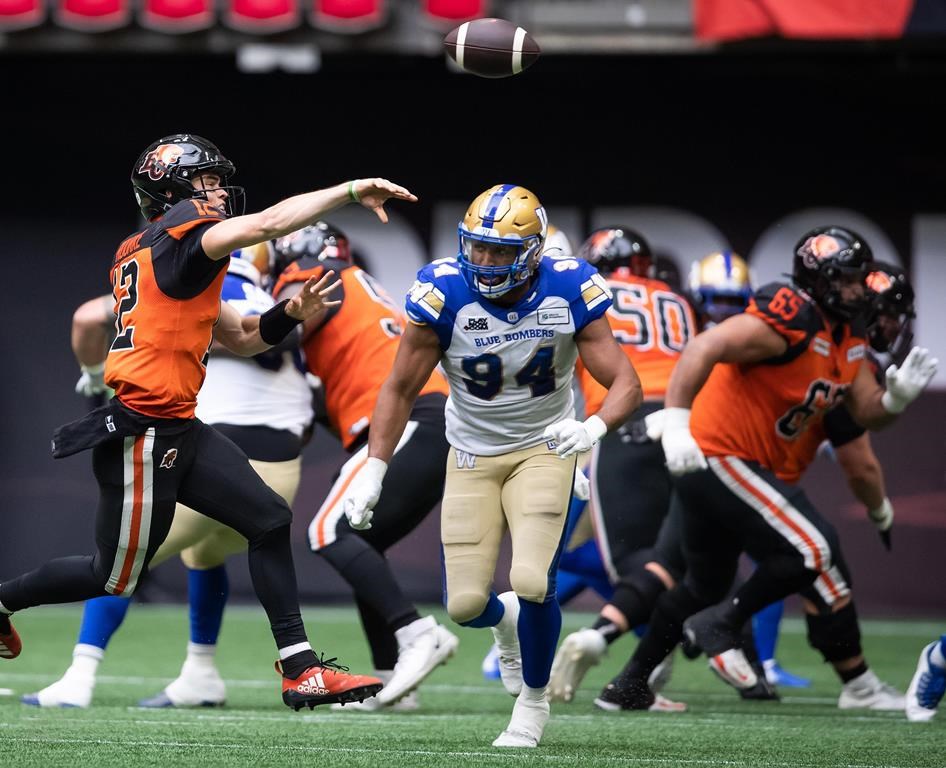 B.C. Lions quarterback Nathan Rourke (12) passes while being pressured by Winnipeg Blue Bombers' Jackson Jeffcoat (94) during the second half of CFL football game in Vancouver, on Saturday, July 9, 2022. THE CANADIAN PRESS/Darryl Dyck