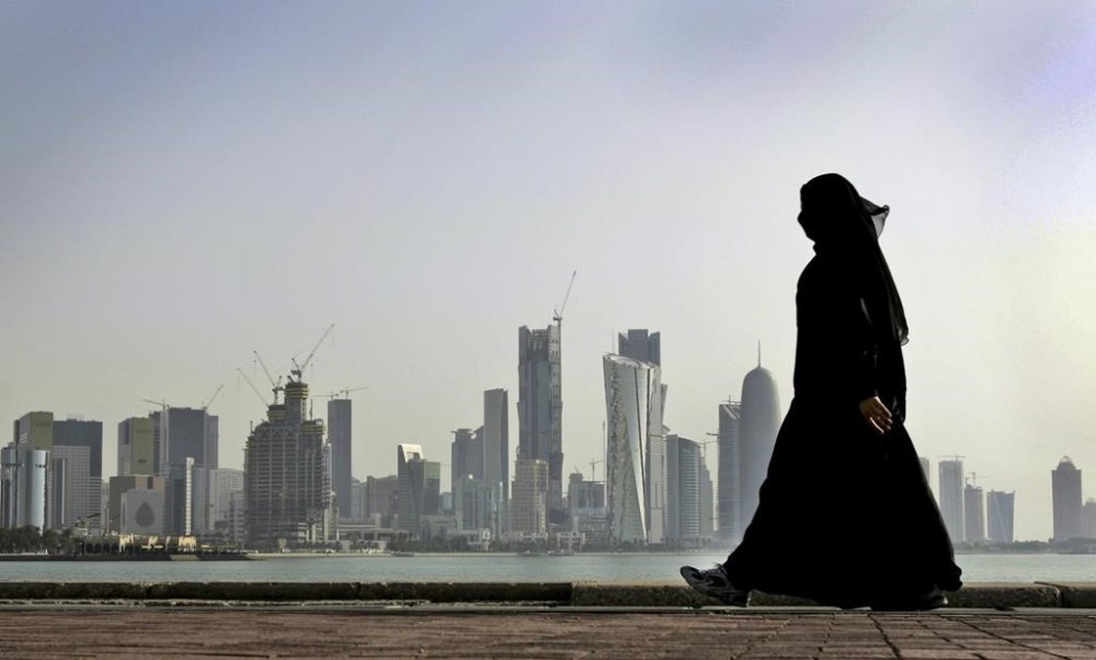 FILE- A Qatari woman walks in front of the city skyline in Doha, Qatar on May 14, 2010. After FIFA awarded the World Cup to Qatar, there were questions about what women would be allowed to wear. The local organizing guide says women must dress modestly with sleeves, long pants or long skirts. (AP Photo/Kamran Jebreili, File)