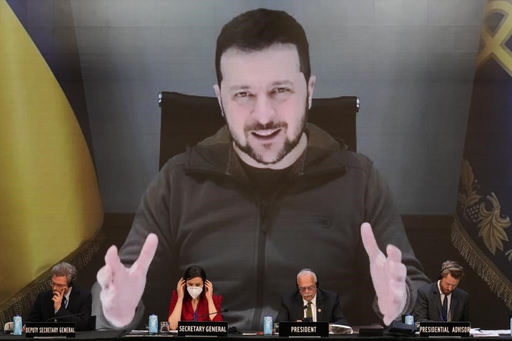 Ukrainian President Volodymyr Zelenskyy appears on a large screen as he speaks via video conference during the 68th Annual Session of the NATO Parliamentary Assembly in Madrid, Spain, Monday, Nov. 21, 2022. (AP Photo/Andrea Comas)