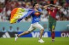 A pitch invader runs across the field with a rainbow flag during the World Cup group H soccer match between Portugal and Uruguay, at the Lusail Stadium in Lusail, Qatar, Monday, Nov. 28, 2022. (AP Photo/Abbie Parr)
