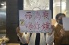 A protester holds up a banner commemorating the victims of a recent Urumqi deadly fire with the words 