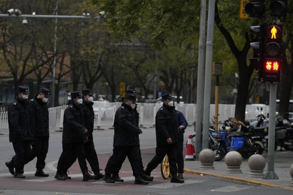 Chinese security personnel walk past a junction near the site of protest the day before in Beijing, Monday, Nov. 28, 2022. Chinese authorities eased some anti-virus rules but affirmed their severe