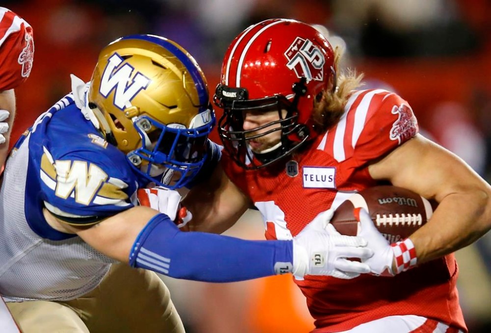 Winnipeg Blue Bombers' Adam Bighill stops Calgary Stampeders' Ante Milanovic-Litre during the second half of their CFL football game in Calgary, Saturday, Nov. 20, 2021. Bighill has signed a two-year contract extension with the Winnipeg Blue Bombers. THE CANADIAN PRESS/Todd Korol