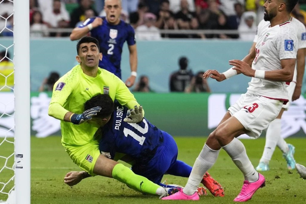 Christian Pulisic of the United States, center, collides with Iran's goalkeeper Alireza Beiranvand, left, after scoring his sides first goal during the World Cup group B soccer match between Iran and the United States at the Al Thumama Stadium in Doha, Qatar, Tuesday, Nov. 29, 2022. (AP Photo/Manu Fernandez)