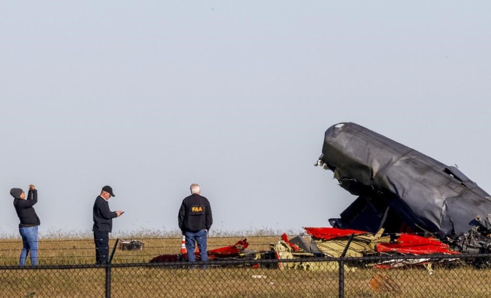 Officials, including those from the Federal Aviation Administration, survey damage from Saturday's crash of a Boeing B-17 Flying Fortress and a Bell P-63 Kingcobra at Dallas Executive Airport on Sunday, Nov. 13, 2022, in Dallas. (Liesbeth Powers/The Dallas Morning News via AP)