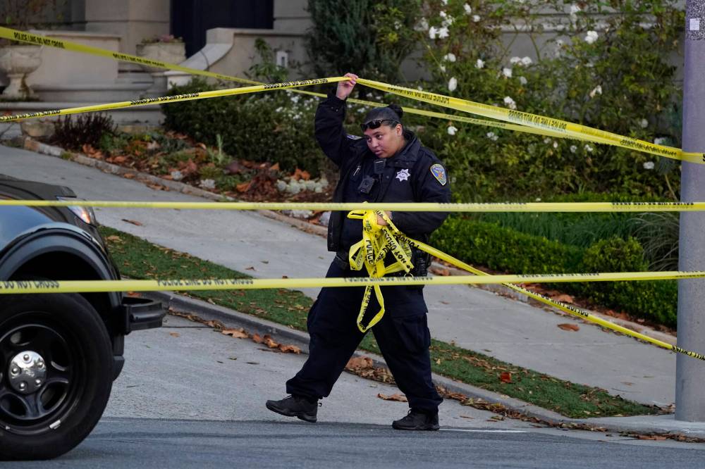 ERIC RISBERG / THE ASSOCIATED PRESS FILES
A police officer rolls out yellow tape on the closed street below the San Francisco home of Paul Pelosi, the husband of U.S. House Speaker Nancy Pelosi.