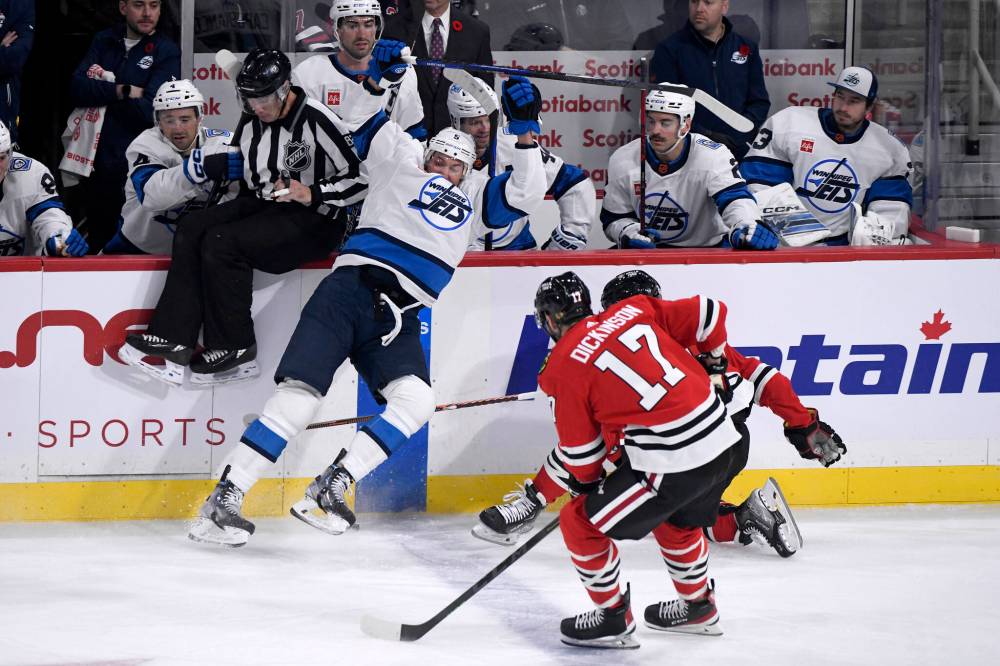 FRED GREENSLADE / THE CANADIAN PRESS
Winnipeg Jets’ Brenden Dillon (5) is upended by Chicago Blackhawks’ Sam Lafferty (24) and Jason Dickinson (17) during the first period.
