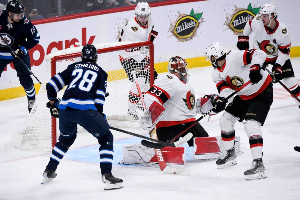 Kevin Stenlund puts the puck behind Senators goaltender Cam Talbot during the first period on Tuesday. (Fred Greenslade / The Canadian Press)