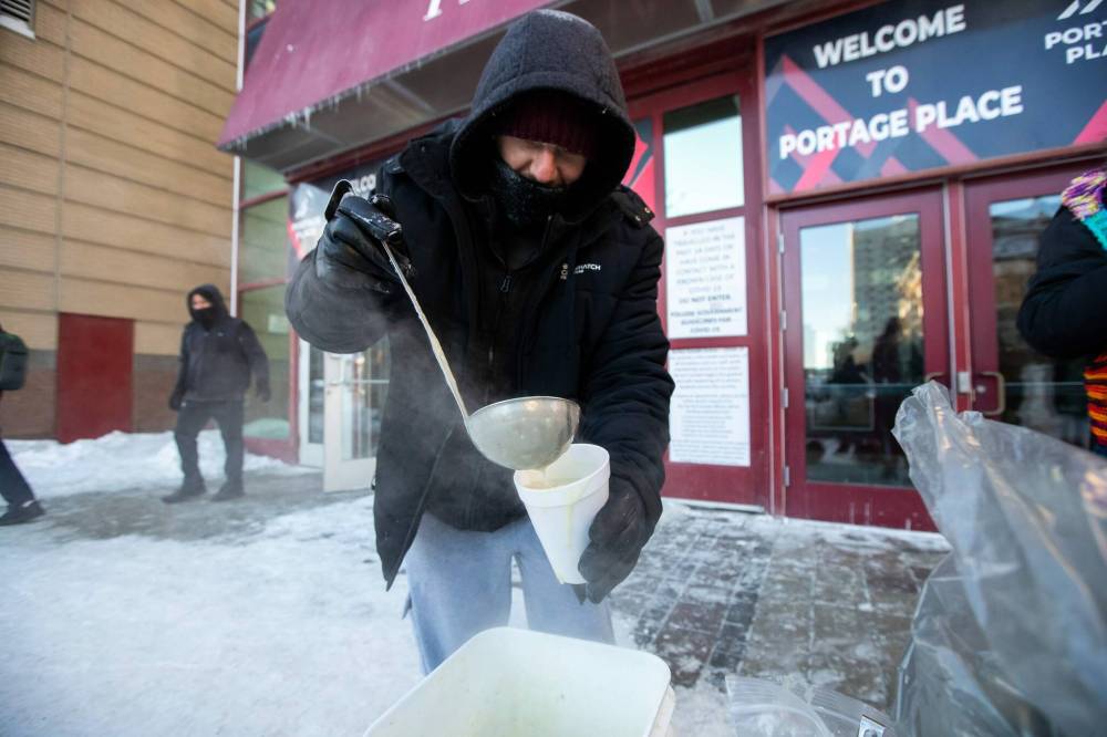 DANIEL CRUMP / WINNIPEG FREE PRESS
Joshua Goddard, a volunteer with Warmer Hearts Winnipeg, ladles out some soup Saturday afternoon in front of Portage Place Shopping Centre.