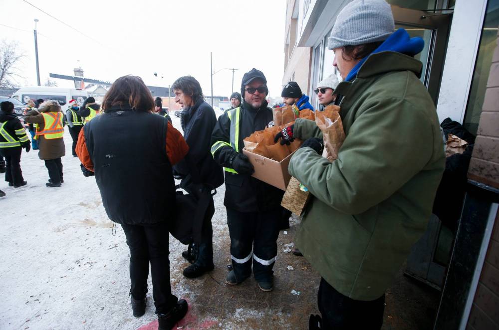 JOHN WOODS / WINNIPEG FREE PRESS
Lorne Proutt, centre, and other volunteers with the Bear Clan hand out winter clothing and lunch outside the Salvation Army on Henry Avenue Sunday.
