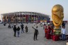 People pose for pictures next to a replica of the World Cup Trophy, right, with the Stadium 974 in the background before the Qatar Fashion United event in Doha, Qatar, Friday, Dec. 16, 2022. (AP Photo/Pavel Golovkin)
