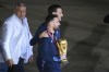 Argentina's captain Lionel Messi walks holding the FIFA World Cup trophy, embraced by coach Lionel Scaloni, after deplaning in Buenos Aires, Argentina, early Tuesday, Dec. 20, 2022. Left is Claudia Tapia, president of Argentina Soccer Association. (AP Photo/Gustavo Garello)
