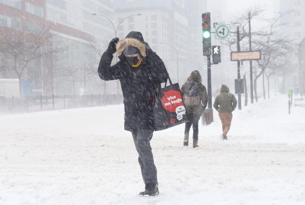 A woman crosses a near deserted street in downtown Montreal during a winter snow storm on Monday, January 17, 2022. THE CANADIAN PRESS/Paul Chiasson