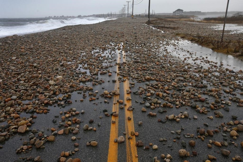 Rocks thrown up by the high surf and wind cover East Beach Road in Westport, Mass., on Friday, Dec. 23, 2022 after a storm surge made landfall across the SouthCoast flooding many coastal areas. (Peter Pereira/The Standard-Times via AP)