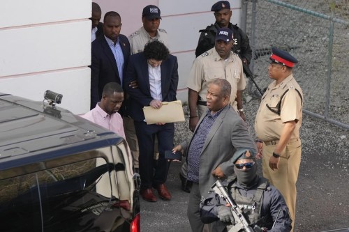 FTX founder Sam Bankman-Fried, center, is escorted out of Magistrate Court into a Corrections van, following a hearing in Nassau, Bahamas, Monday, Dec. 19, 2022. (AP Photo/Rebecca Blackwell)