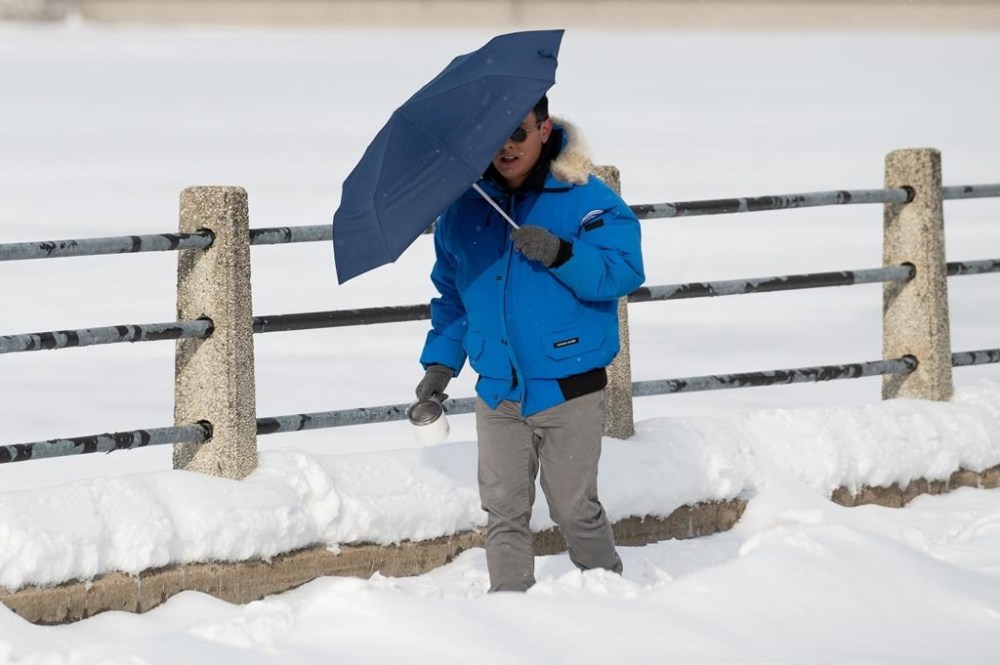 A person uses an umbrella to shield themselves from strong winds on Christmas Day in Ottawa, Sunday, Dec. 25, 2022. Thousands of Canadians are spending another day in the cold and dark, as hydro crews continue working to restore electricity to those affected by the power outages caused by fierce winter storms last week. THE CANADIAN PRESS/Spencer Colby