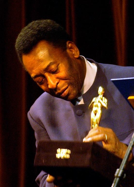 FILE - Brazilian soccer legend Pelé looks at a statue given by the Rio de Janeiro Gov. Rosinha Matheus, at the Municipal Theater in Rio de Janeiro, Monday, June 21, 2004. The recognition was given during the premier of the movie