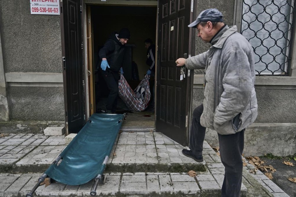Local residents carry the body of a 20-year-old man, killed in Russian shelling in Kherson, Ukraine, Thursday, Jan. 5, 2023. (AP Photo/LIBKOS)