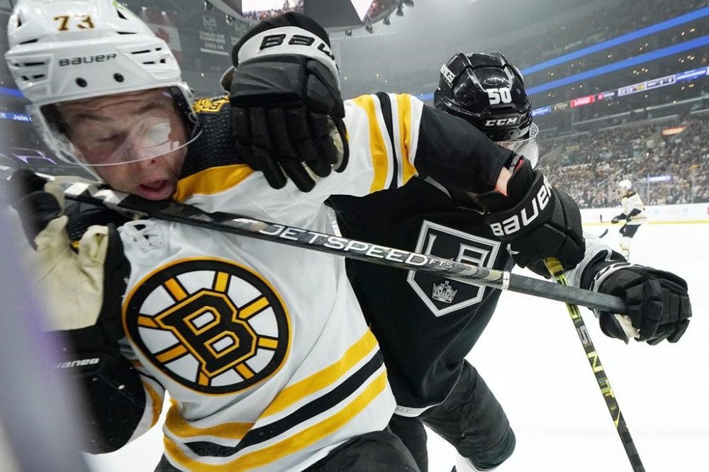 Boston Bruins defenseman Charlie McAvoy, left, takes a stick to the face from Los Angeles Kings defenseman Sean Durzi during the first period of an NHL hockey game Thursday, Jan. 5, 2023, in Los Angeles. (AP Photo/Mark J. Terrill)