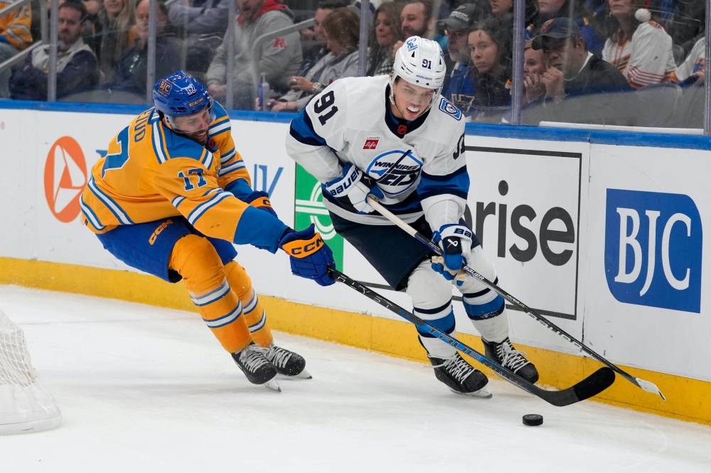(AP Photo/Jeff Roberson)
                                Winnipeg Jets’ Cole Perfetti and St. Louis Blues’ Josh Leivo chase after a loose puck along the boards during the third period.